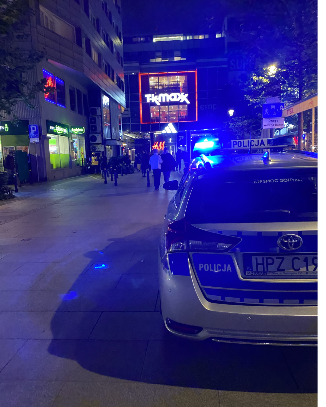 A police car with its lights on, on a city street at night